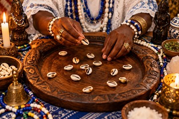 B&uacute;zios dispostos sobre uma esteira de palha, com uma vela acesa e um pano branco ao lado