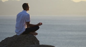 Homem em medita&ccedil;&atilde;o ao ar livre ao nascer do sol, em meio &agrave; natureza