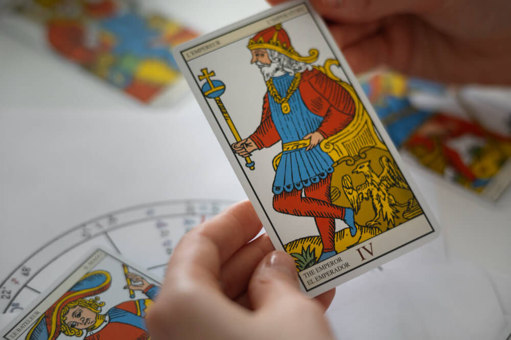 Carta Quatro de Copas no Tarot: jovem sentado sob uma &aacute;rvore recusando a ta&ccedil;a oferecida