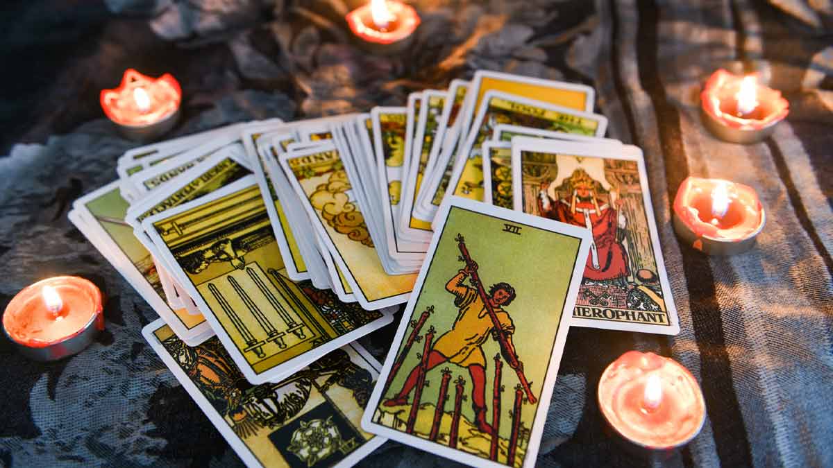 Cartas de tarot espalhadas sobre uma mesa com uma vela, representando os mitos e verdades sobre o tarot
