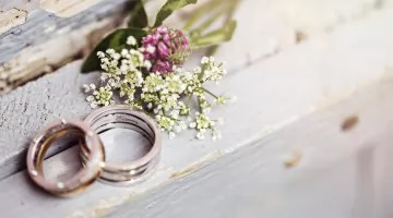 Sonhar com casamento: alian&ccedil;as e buqu&ecirc; de noiva sobre uma mesa