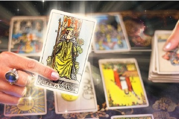 Pessoa em frente a um notebook, com cartas de tarot e um curr&iacute;culo sobre a mesa, representando a busca por emprego