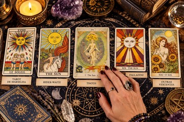 Quatro baralhos de Tarot de vertentes diferentes, lado a lado sobre uma mesa de madeira